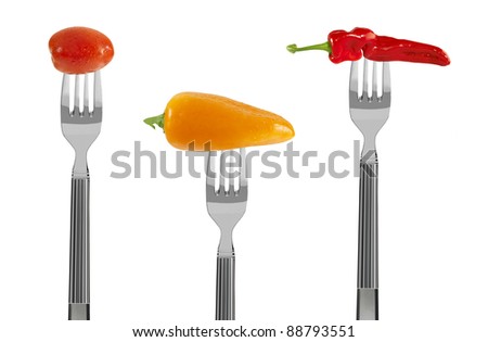 fresh red and yellow baby vegetables on forks, isolated on white