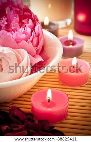 A bowl full of beautiful pink aromatherapy flowers with candles. Spa scene. Royalty-Free Stock Photo #88825411