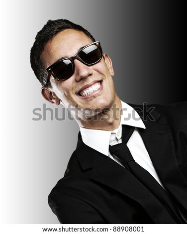 portrait of young business man with suit and sunglasses against a black background