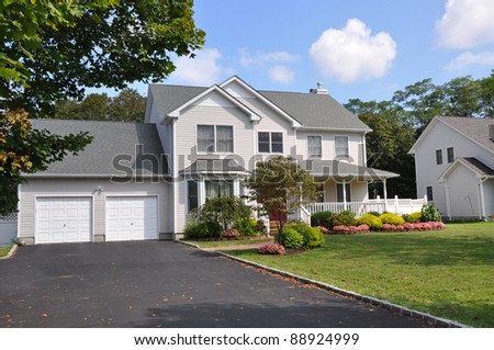 Suburban Two Car Garage Large Siding Home with Double Wide Blacktop Driveway Front Yard on Sunny Blue Sky Cloud Day Royalty-Free Stock Photo #88924999
