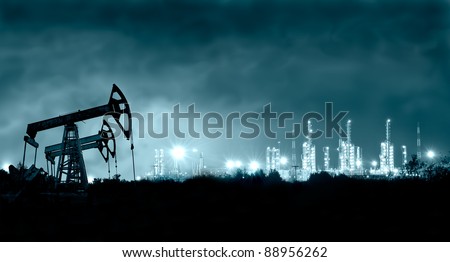 Group oil rigs and brightly lit industrial site at night. Toned.