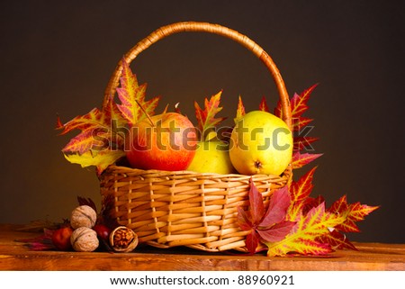 beautiful autumn harvest in basket and leaves on brown background