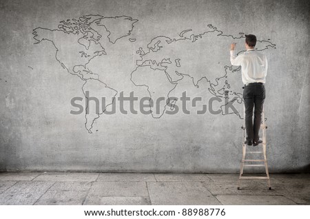 Businessman on a ladder drawing a world map
