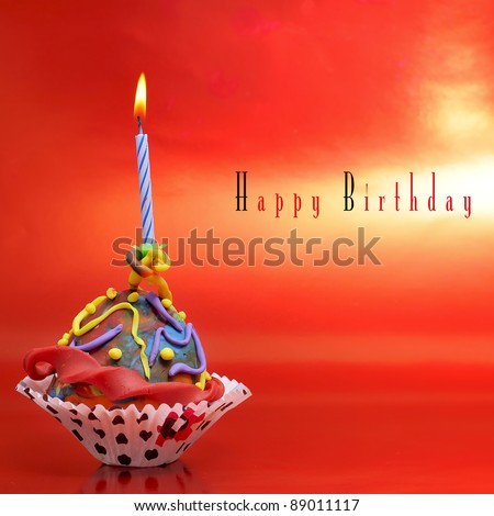 a plasticine cupcake with a candle on a red background with sentence happy birthday