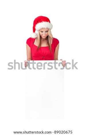 Santa girl holding blank sign billboard. Advertising photo of young smiling Christmas woman in Santa hat showing paper sign. Caucasian female model isolated on white background