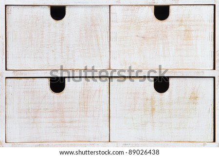 Four white wooden drawers with black holes