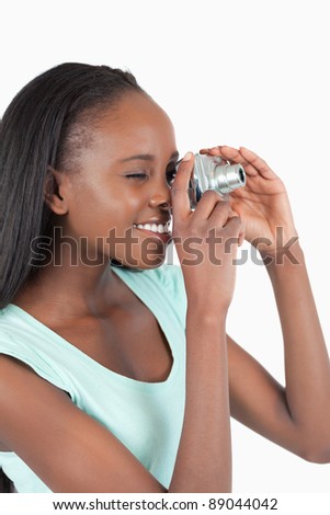 Side view of young woman taking a photo against a white background