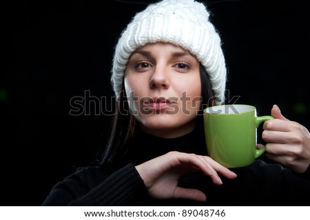 a beautiful young attractive charming girl in a white hat and black gloves with a green mug in hand, on a black background