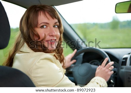 Young smiling beautiful woman sitting in the new car