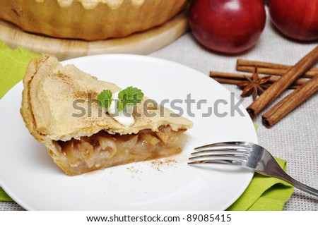 A slice of apple pie with whipped cream and mint on white plate