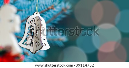 Christmas decoration of woody angel and handmade bell on the blue background of fir-tree having much space for text