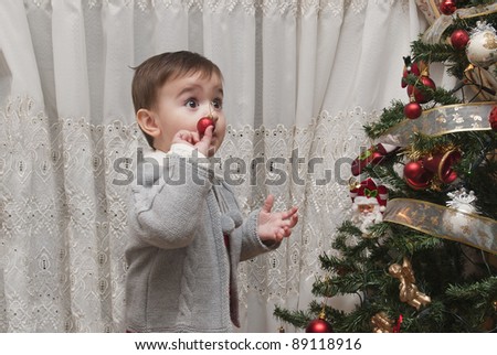 Little child impressed by his first time decorating the Christmas tree.