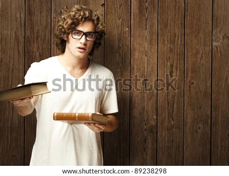 portrait of young student holding books against a wooden wall