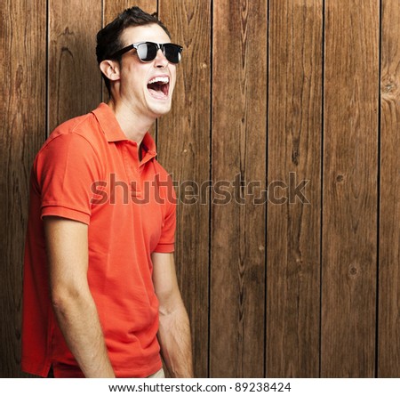 portrait of young man shouting and joking against a wooden wall