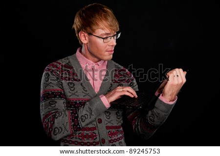 a handsome young stylish brutal business man holding a laptop in hand on a black background