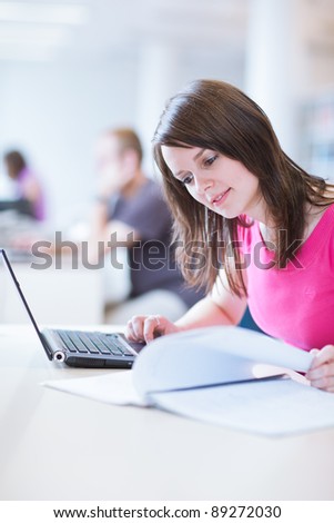 in the library - pretty female student with laptop and books working in a high school library  (color toned image)