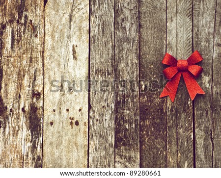 Christmas background with a sparkling red Christmas bow on a grunge wooden backdrop with copy space.