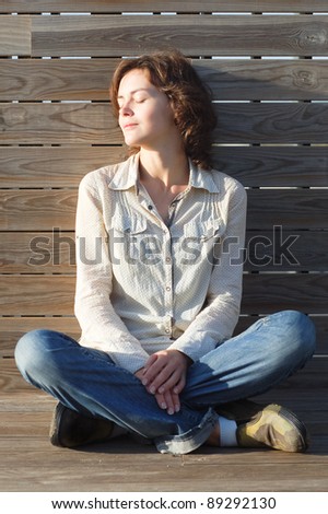 Young woman sitting on the wooden background