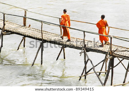 Monks crossing a wooden bridge in Luang Prabang, Laos