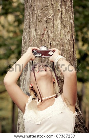 Beautiful young girl taking pictures with a old vintage camera
