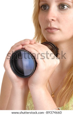 A beautiful girl with blond hair holding a photo lens in her hand, with a serious look, in closeup over white background.