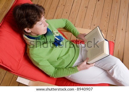 Middle aged woman is reading a book. Studio picture