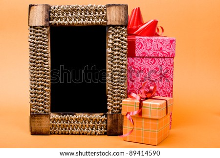 Photo frame and gift box with ribbon on orange background.