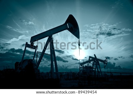 Oil and gas industry. Silhouette oil pumps on a sunset sky background. Toned.
