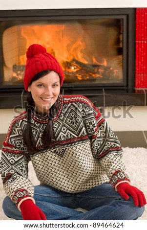 Happy woman warming up by home fireplace wear Christmas sweater