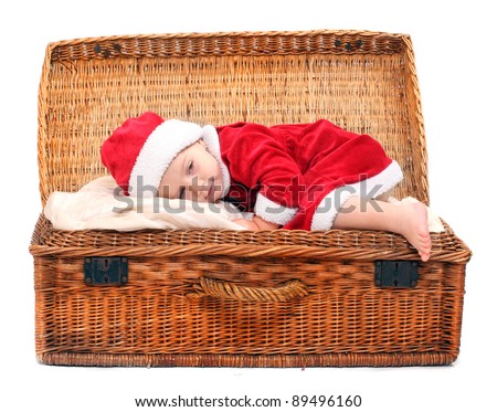 Funny picture of a little child in Santa Claus costume sleeping in a vintage gift box.
