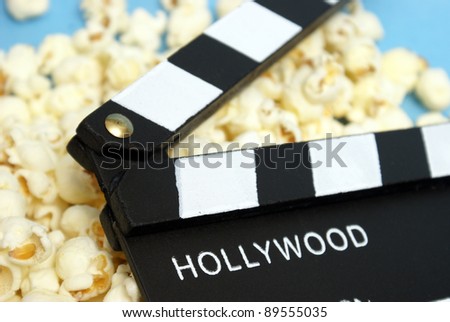 A movie clapboard rests on a pile of fresh popcorn.