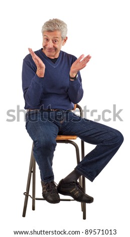 Happy senior man smiles, looks up, and raises his hands as if to clap. Wearing dark blue jeans and a long sleeved shirt, he sits on a stool. Isolated on white, vertical format.
