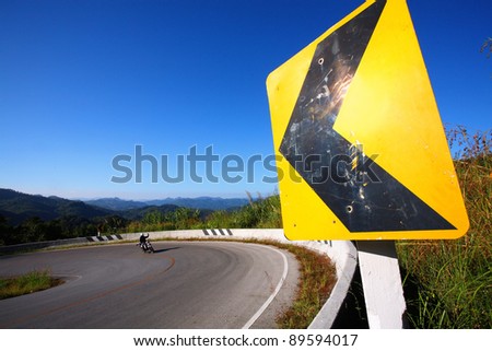 danger curve road sign with blue sky