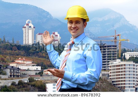 Young architect wearing a protective helmet standing on the mountains building outdoor background