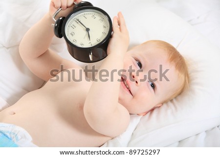 child with an alarm clock lying on the bed, and wishes everyone a good morning