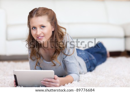 Smiling woman lying on the carpet with her tablet
