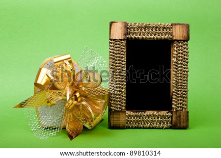 Wood photo frame and heart gift box with ribbon on green background.