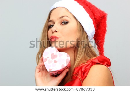 Beautiful Young Happy Christmas Woman holding a heart shaped gift box neutral background