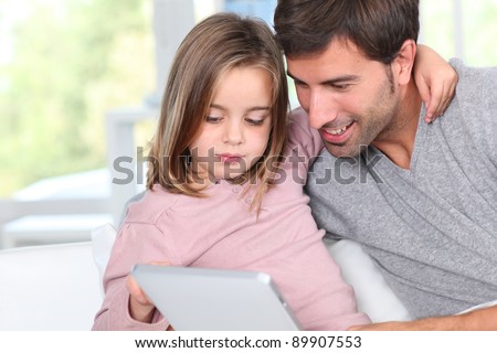Father and child using electronic tablet at home