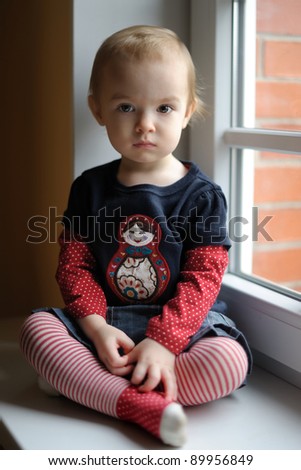 Two years old toddler girl sitting by the window