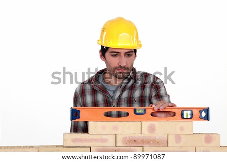 Mason checking level of a brick wall