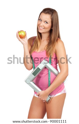 Lovely young woman standing and holding apple and weight scale, isolated on white