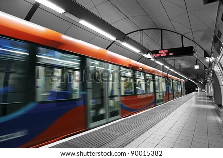 A subway train in motion arriving at a London underground train station. Royalty-Free Stock Photo #90015382