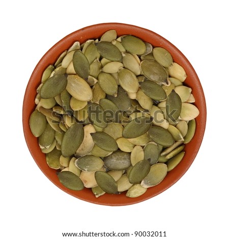 Ceramic bowl full of pumpkin seeds isolated on white background