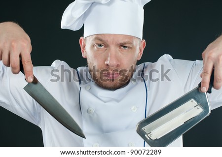 Serious caucasian chef with kitchen knives, dark background
