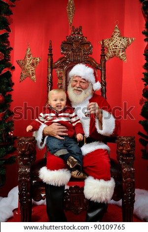 Baby boy sitting on Santa's lap at Christmas time. Royalty-Free Stock Photo #90109765
