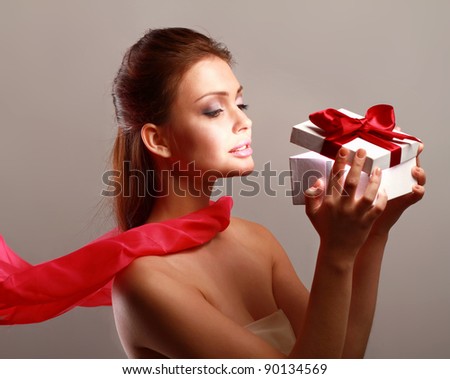 Young girl opening x-mass present isolated on grey background