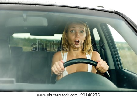 Fright face of an young woman sitting in the car and holds the wheel