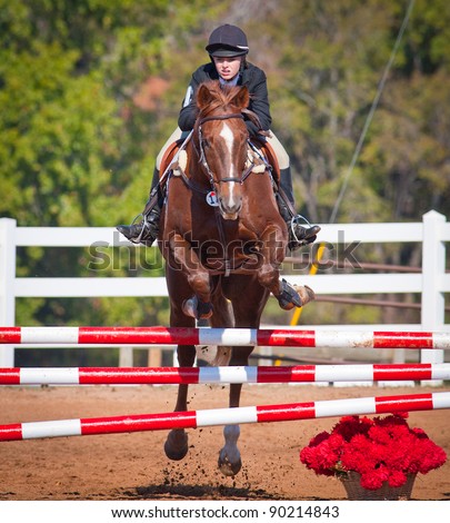 Young woman jumps high during a show jumping event Royalty-Free Stock Photo #90214843