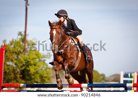 Young teen jumps horse over jump in arena Royalty-Free Stock Photo #90214846